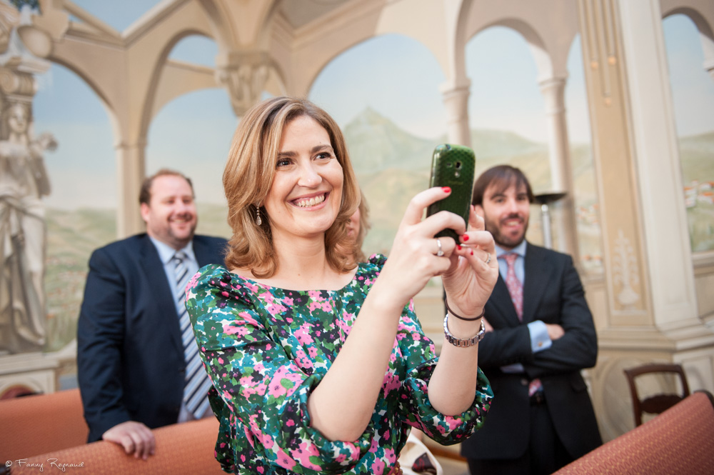 Photographie en couleur d'une invitée qui photographie avec son smartphone les mariés à la mairie de clermont-ferrand. Image spontanée professionnelle.