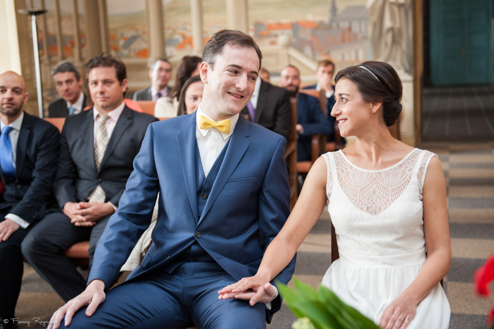Regard et sourire complices des mariés qui se tiennent la main, pendant le mariage civil à la mairie de clermont-ferrand.