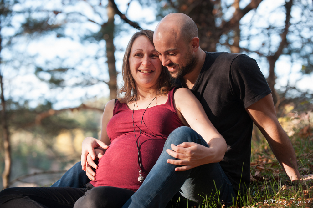 Moment complice en forêt d'un couple attendant en enfant. Shooting grossesse en extérieur par un photographe professionnel dans le puy-de-dome.