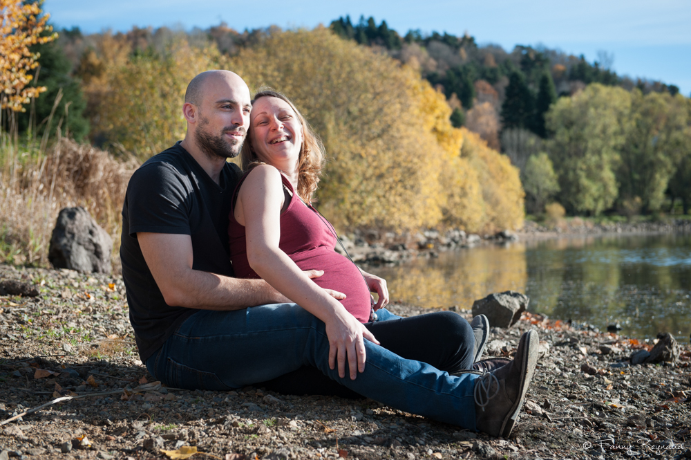 Photographie professionnelle d'un couple attendant un enfant assis au bord du lac de la cassière dans le puy-de-dome. Séance en extérieur en automne par Fanny Reynaud photographe professionnelle à clermont-ferrand.