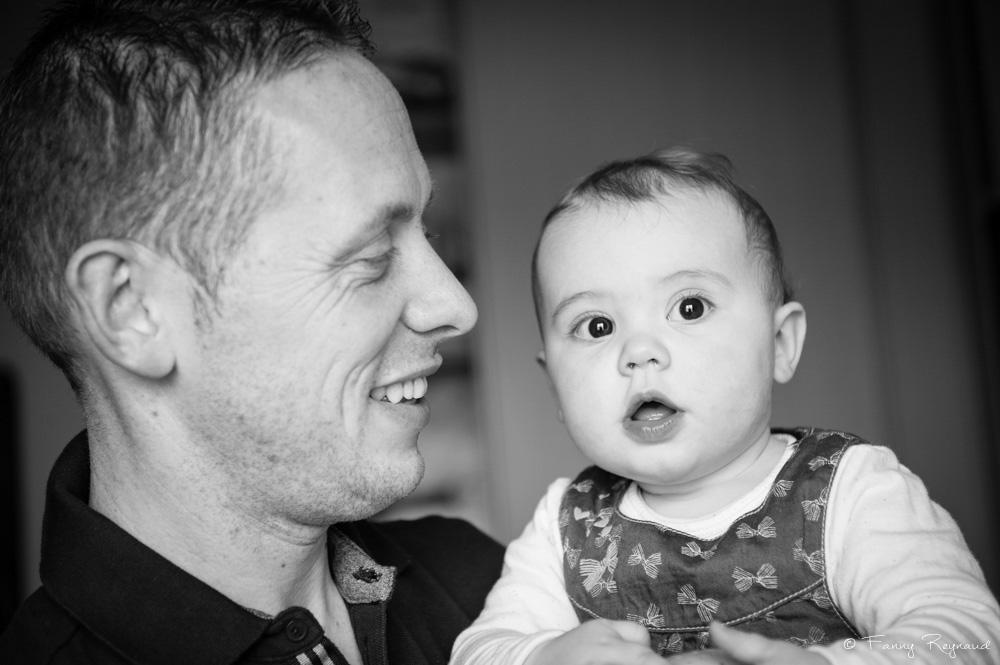 Photo d'une petite fille dans les bras de son papa, séance de portrait de famille à domicile dans les environs de clermont-ferrand par un photographe professionnel.