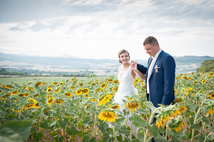 Photo de couple de mariage dans un champ de tournesol avec la chaine des puys dans le village de montpeyroux en auvergne.