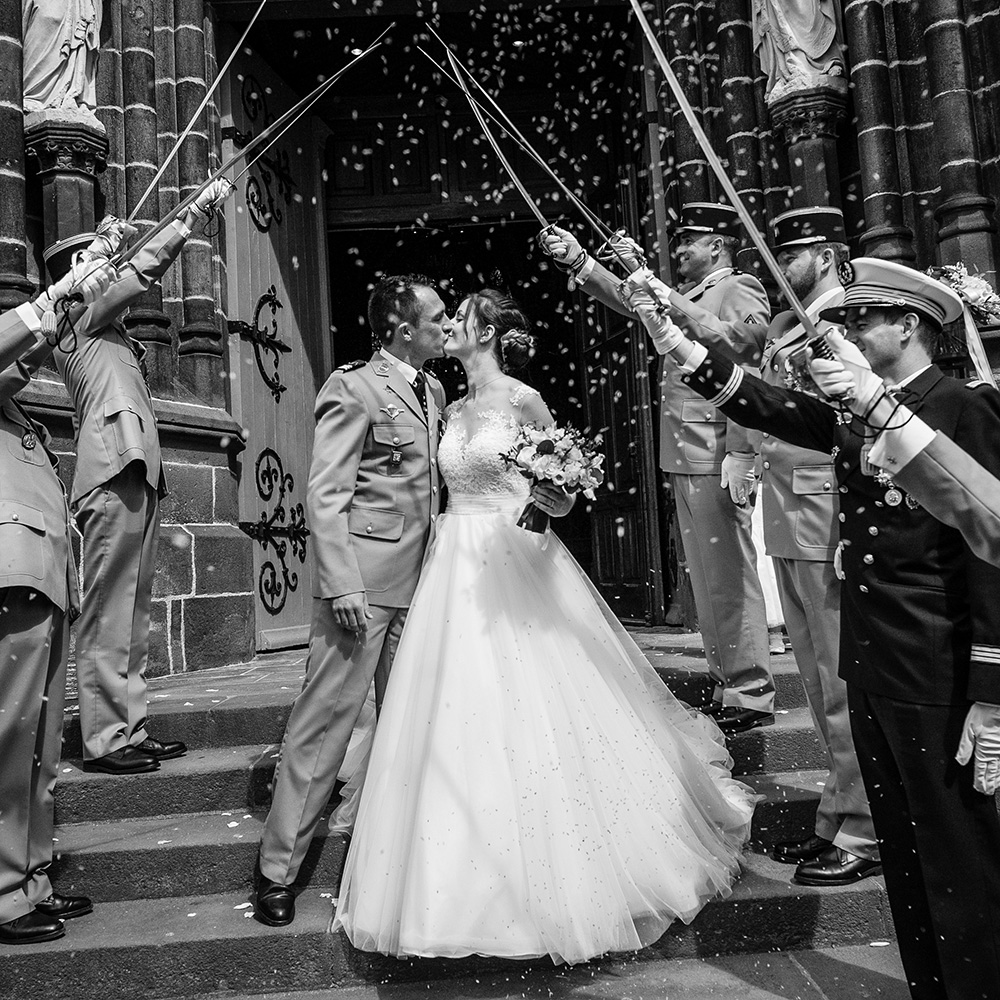 Sortie de l'église saint eutrope à clermont-ferrand d'un mariage de militaire avec une haie d'honneur de sabres.