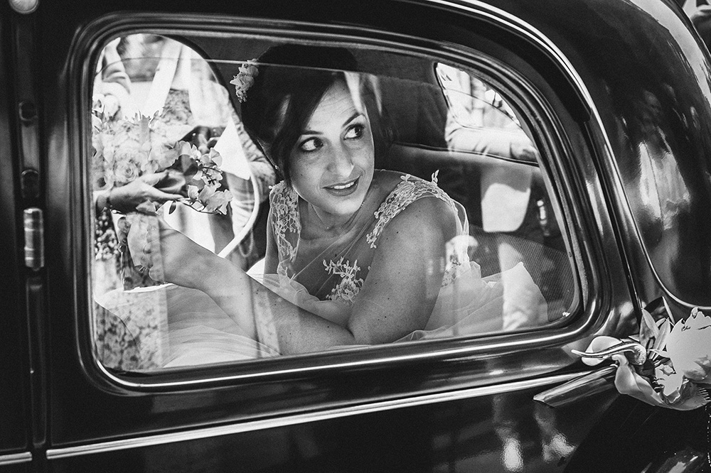 la mariee regarde par la fenetre avant de sortir d'une voiture de clermont, photographie professionnelle en noir et blanc à clermont ferrand