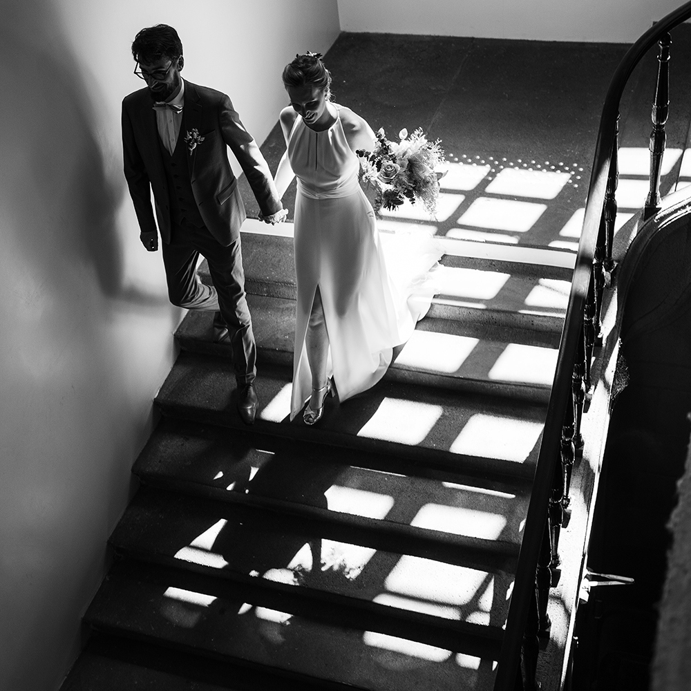 Photo professionnelle en noir et blanc d'un couple de mariés descendant les escaliers de la mairie de clermont-ferrand.