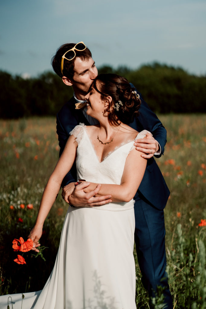 photographie d'un couple de mariés dans un champ de coquelicots en auvergne