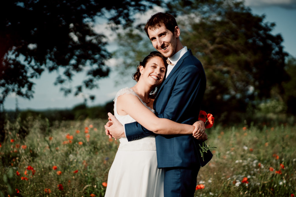 photographie de mariés dans un champ de coquelicots près du chateau de feligonde a sayat